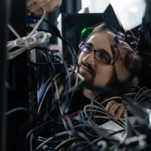 A skilled IT technician organizing tangled cables at his workstation in an office environment.